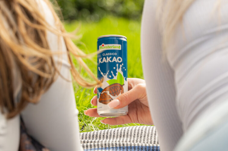 Frauen picknicken und halten Kakaomilch am See