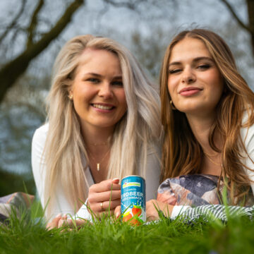 2 glückliche Frauen auf Wiese mit Erdbeermilchdose