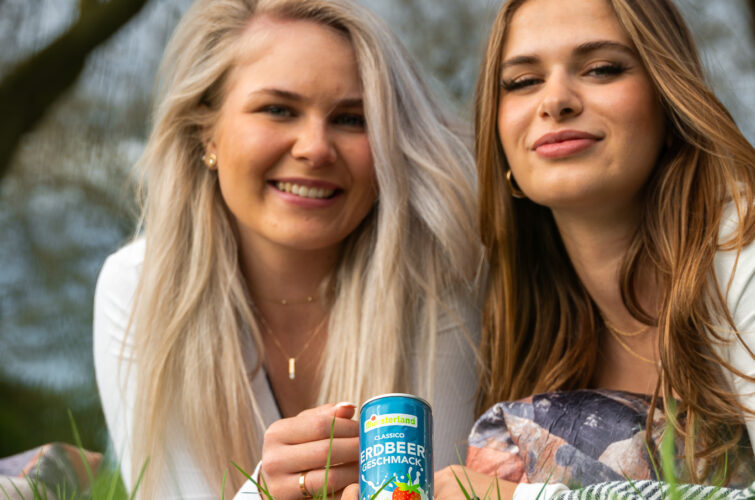 2 glückliche Frauen auf Wiese mit Erdbeermilchdose